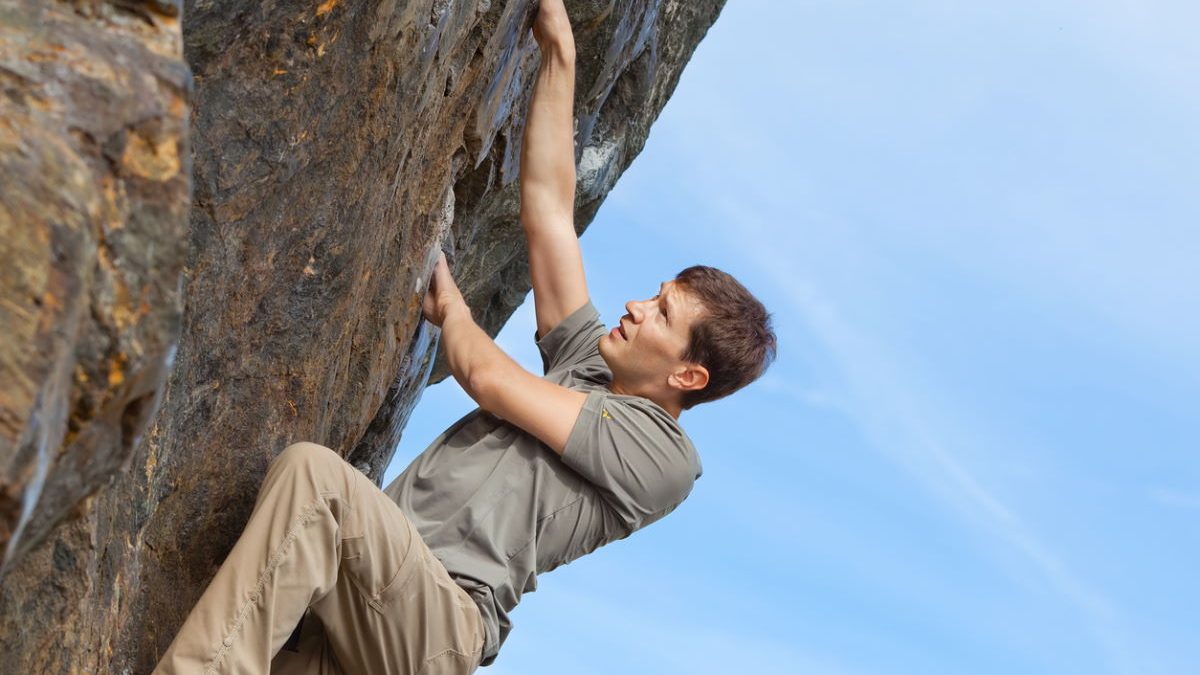 young healthy man rock climbing or bouldering outdoors