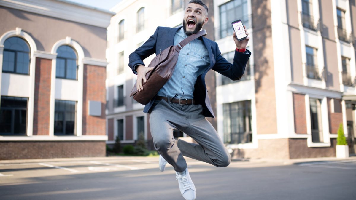 Handsome man jumping. Handsome man jumping after reading approving message from successful company