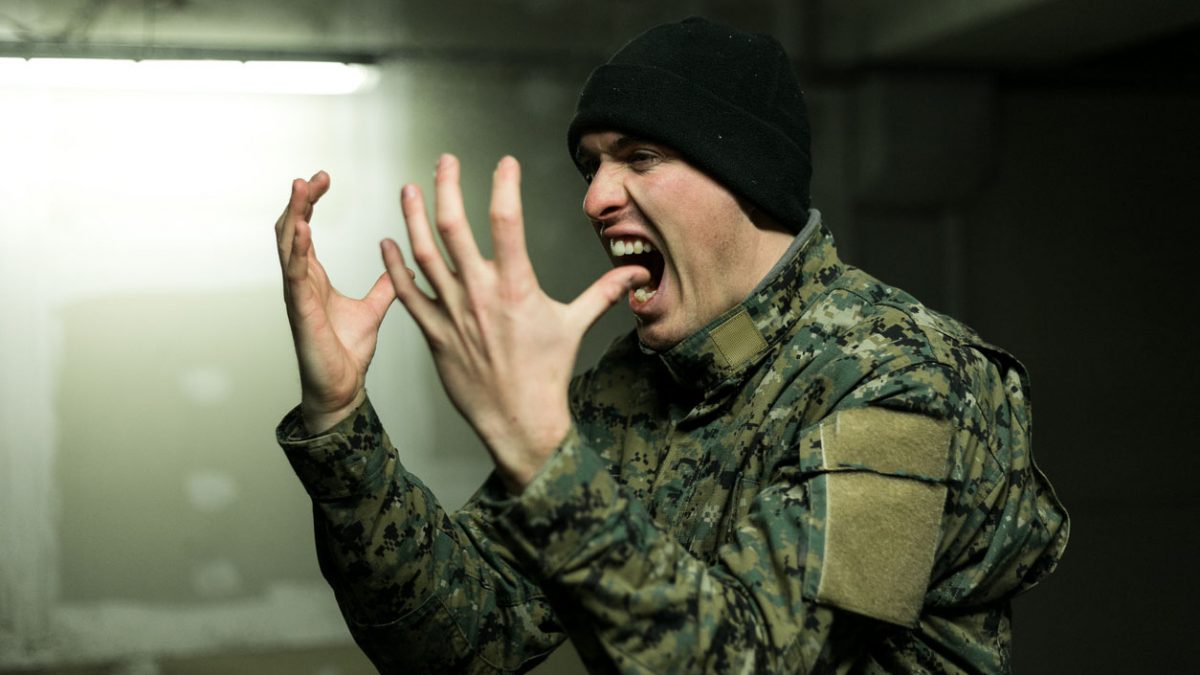 Army soldier screaming, he is scared and frustrated.