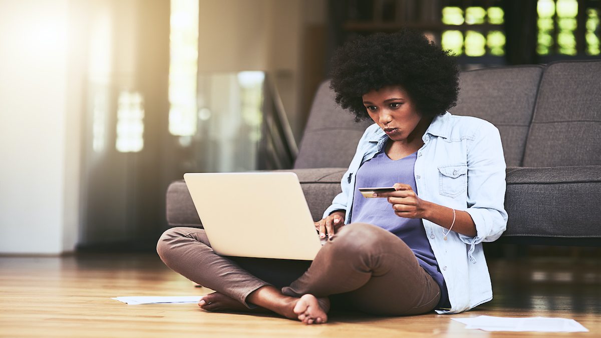 Shot of a young woman using a laptop and credit card at home