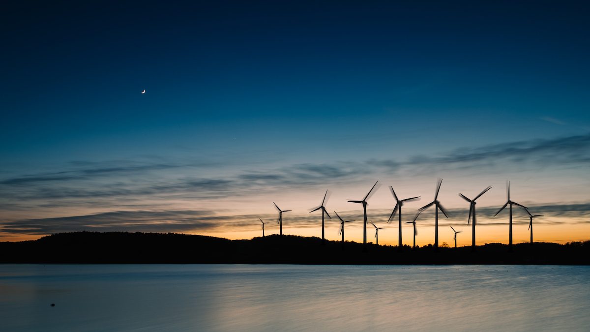 Windmills in the sunset. Wind turbines motion landscape at sunset with plane in background